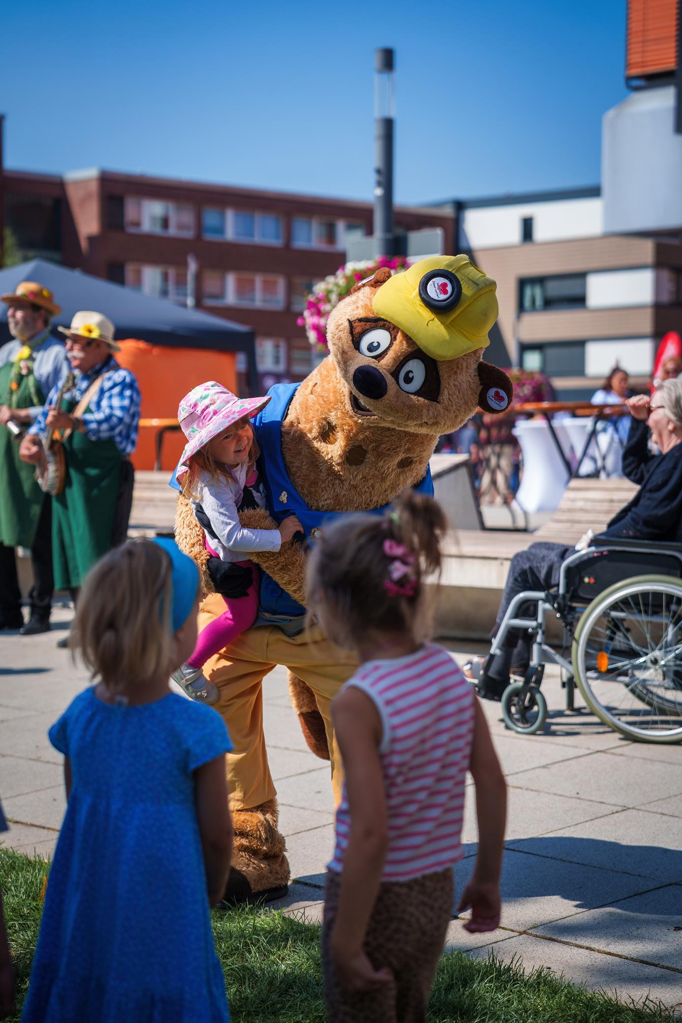 Kalli, das Maskottchen der Stadt Kamp-Lintfort, spielt mit Kindern auf dem Stadtgartenfest 2025.